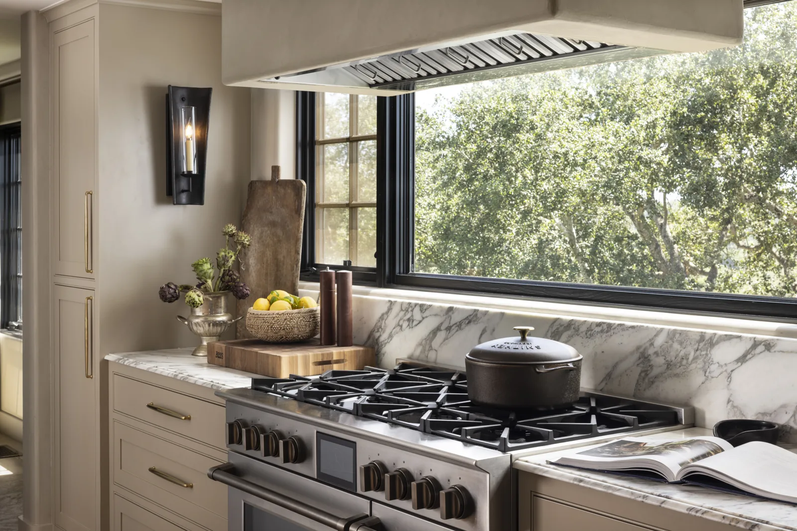 Kitchen range beneath a broad window with marble counters and backsplash at Adobe Canyon Farmhouse