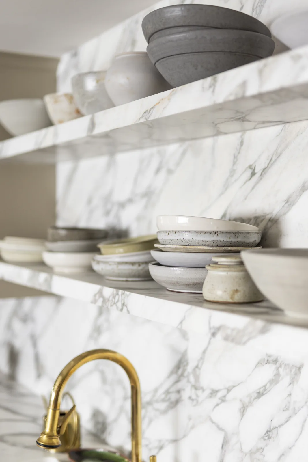 Marble kitchen shelves displaying ceramic bowls and plates at Adobe Canyon Farmhouse