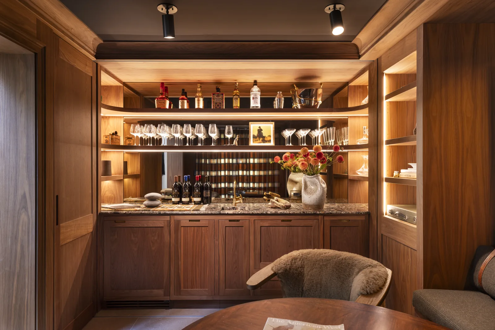 Custom wood bar with illuminated shelves and stone countertop at Adobe Canyon Farmhouse