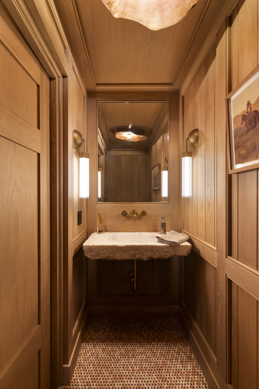 Wood-paneled powder room with a stone basin and wall-mounted fixtures at Adobe Canyon Farmhouse
