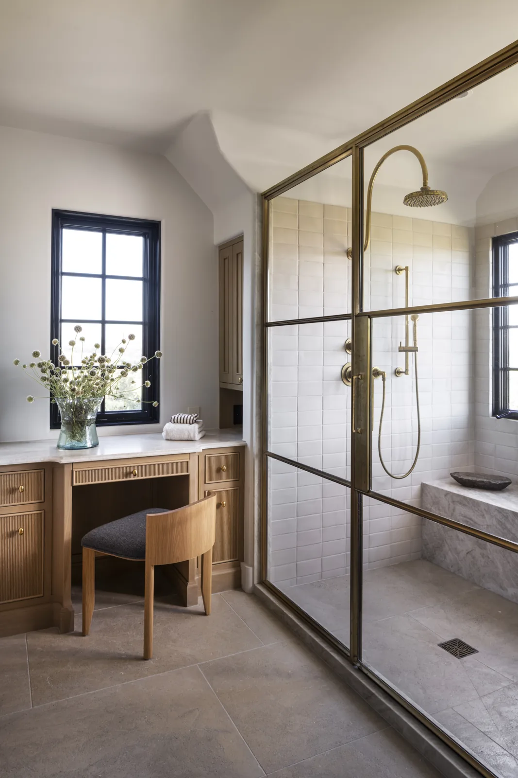 Bathroom vanity and brass-framed glass shower beside tall windows at Adobe Canyon Farmhouse