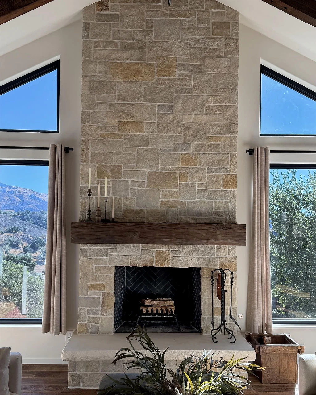 Stone fireplace with timber mantel and tall windows
