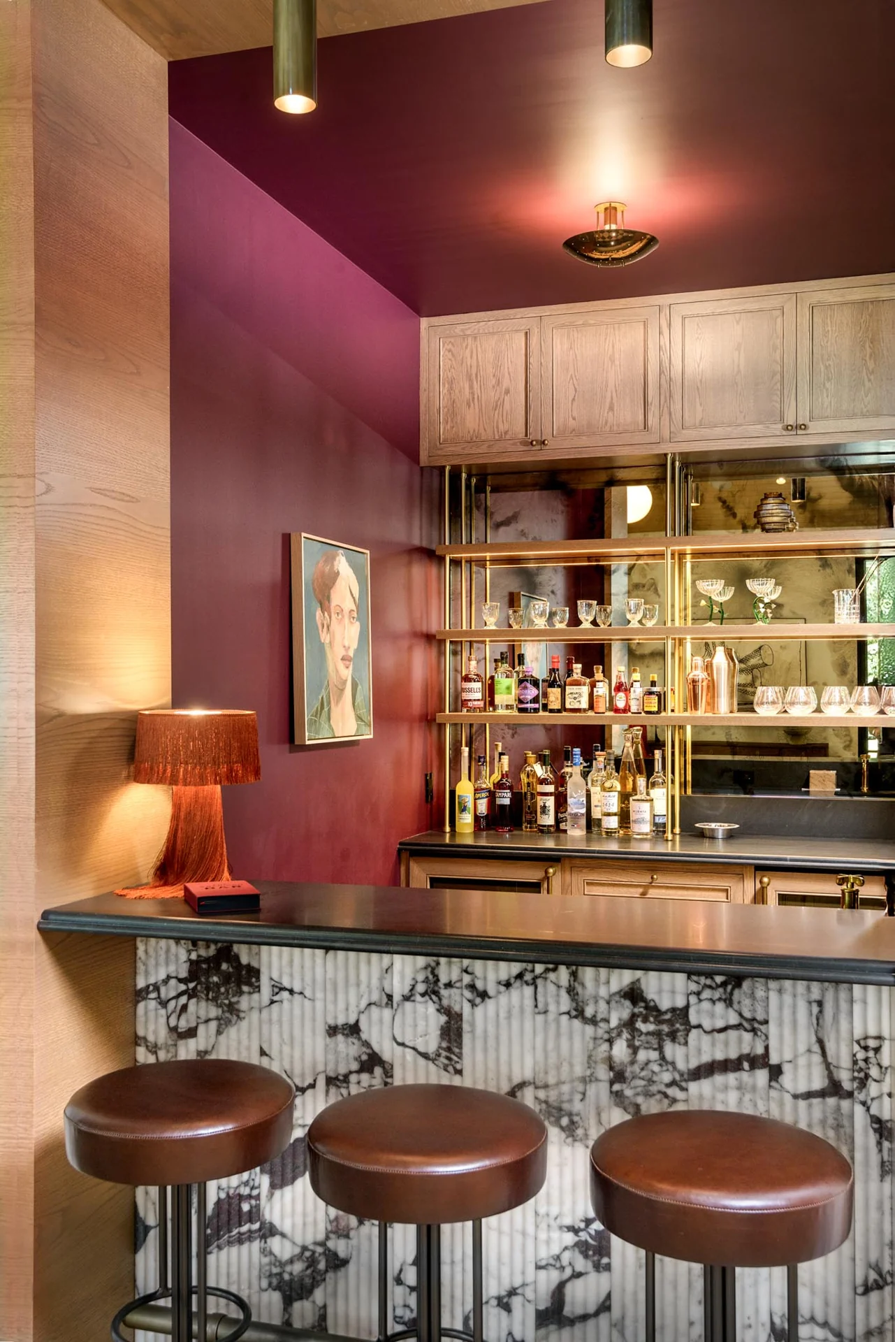 Custom bar with marble, bronze-toned detailing, and rich red walls