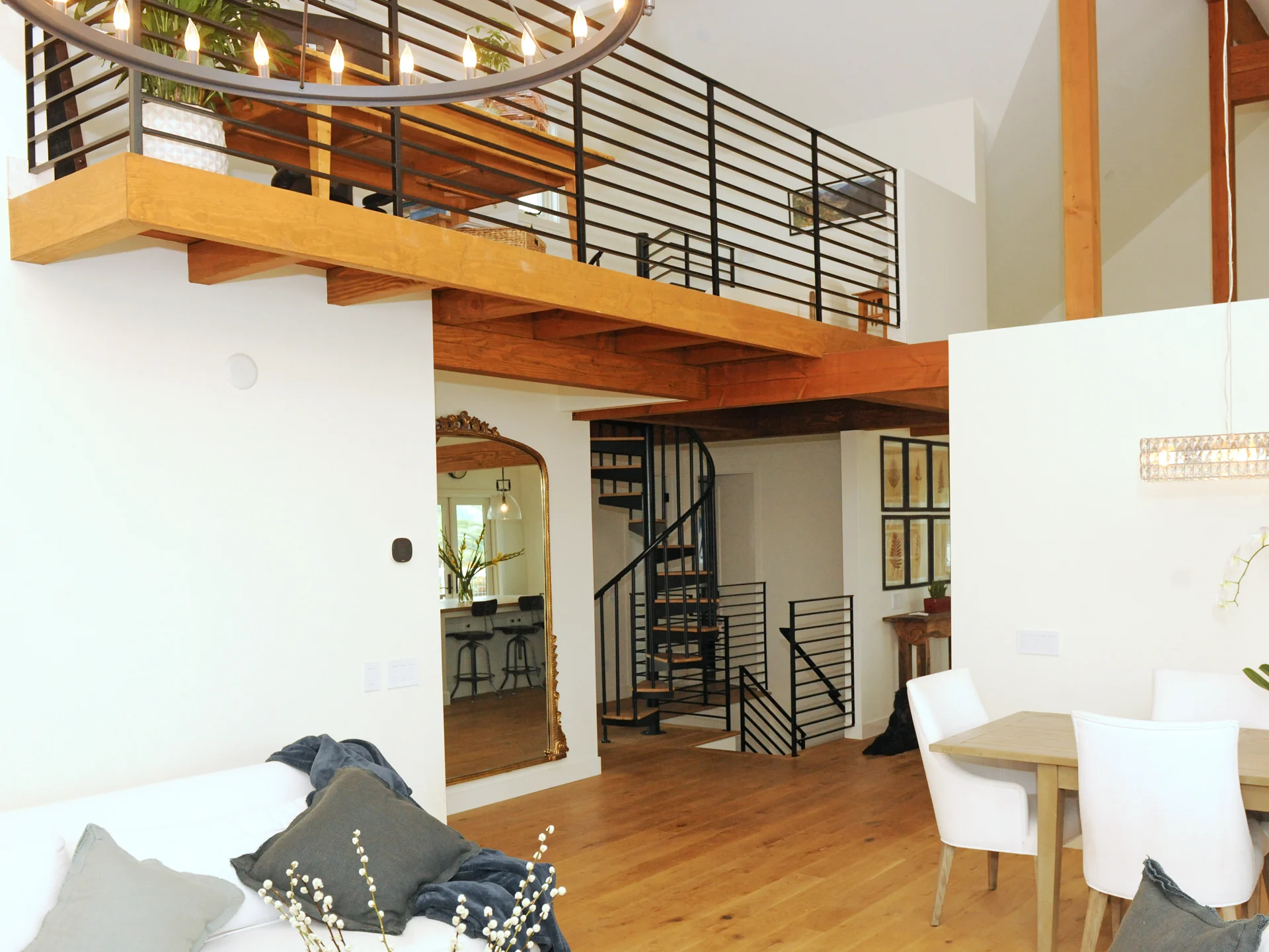 Open living and dining area beneath a timber loft with a spiral staircase