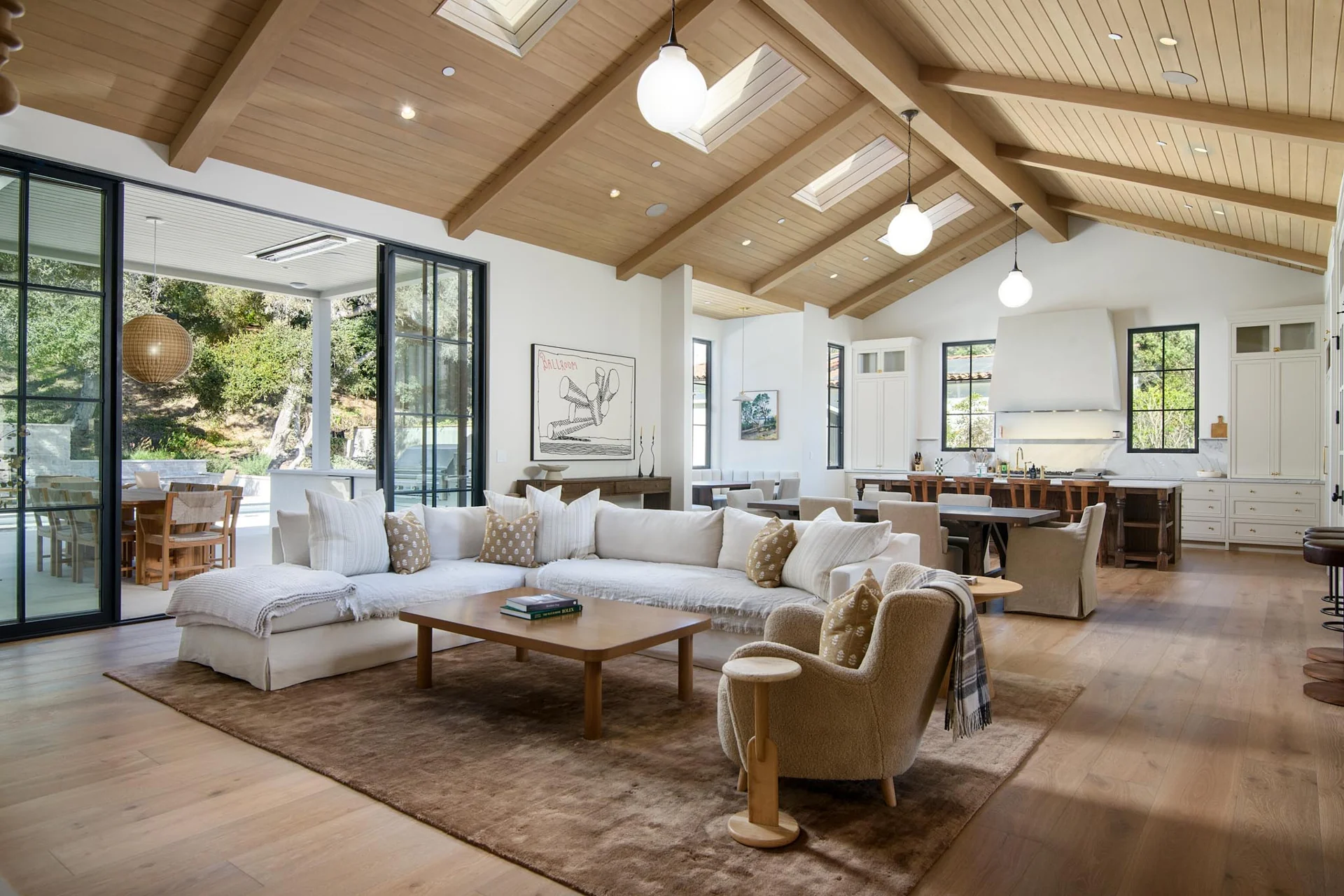 The great room, with vaulted timber ceilings and open connections to the kitchen and terrace