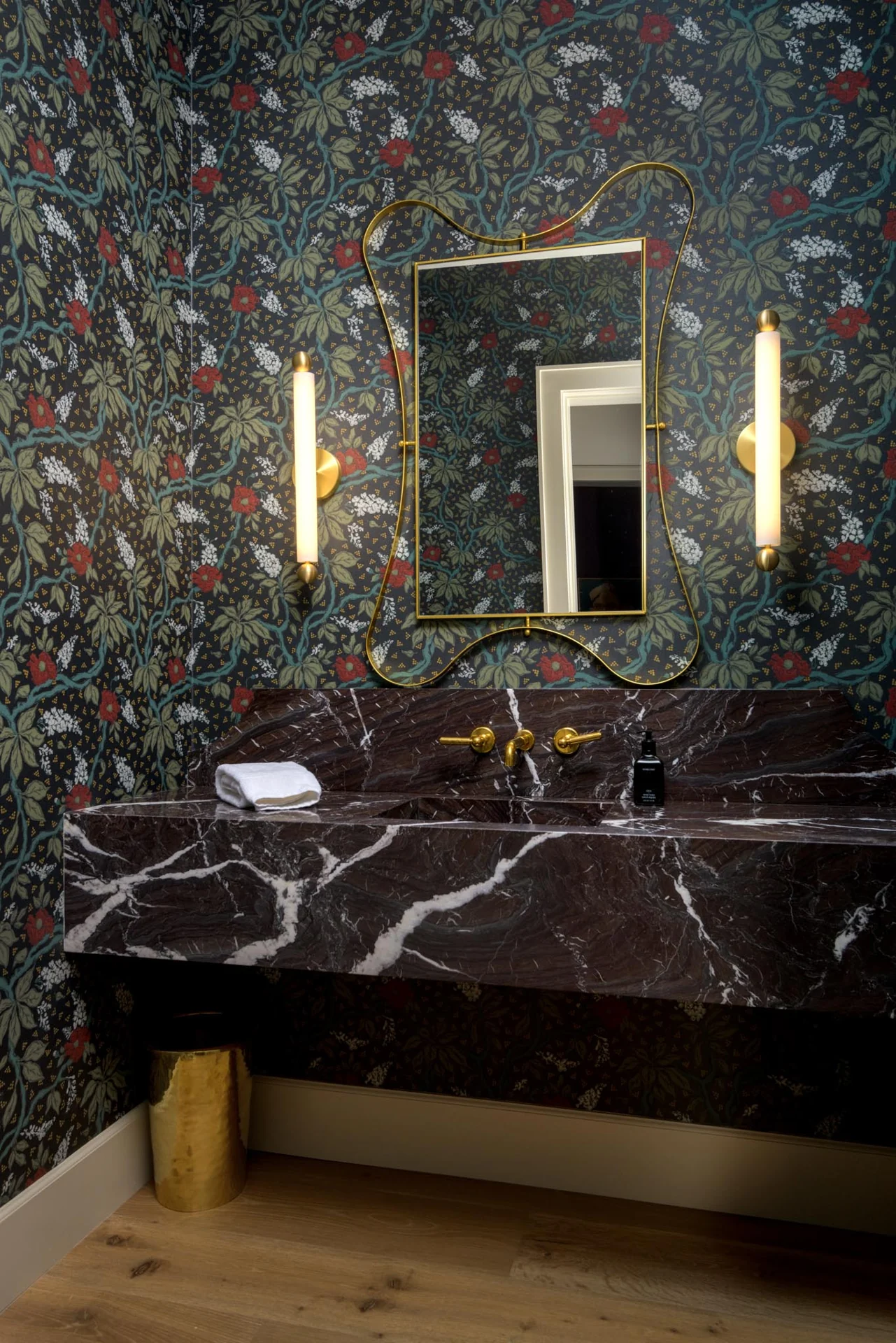 Powder room with patterned wallpaper and a richly veined stone vanity