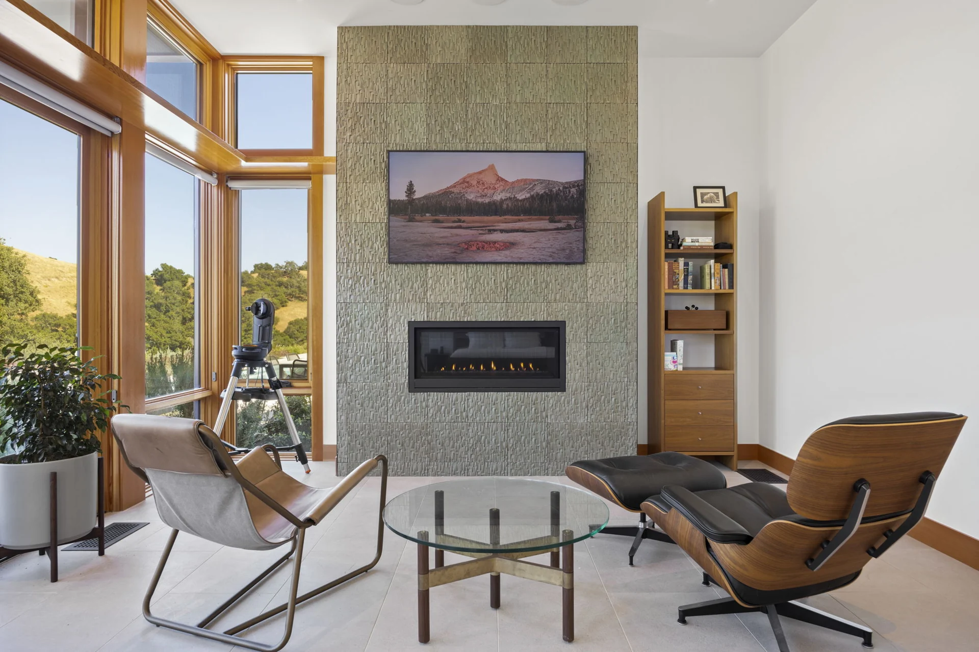 Living room fireplace with tall windows overlooking the hills