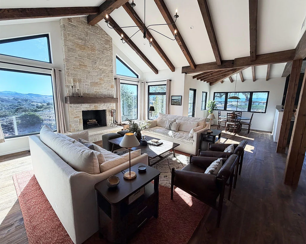 Living room with exposed beams, stone fireplace, and mountain views