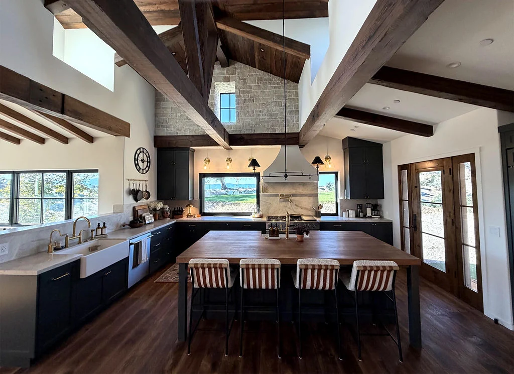 Kitchen with dark cabinetry, timber beams, and a large wood island