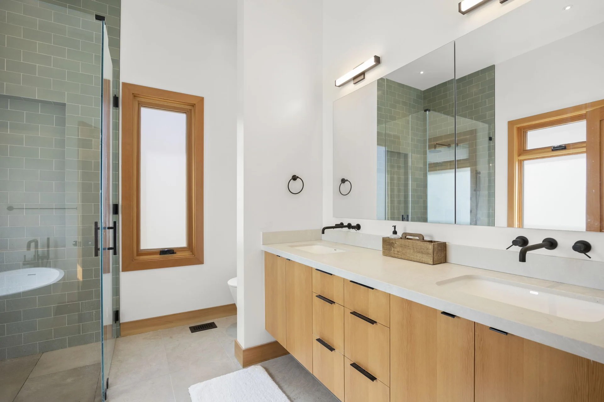 Bathroom with double vanity and green tile shower