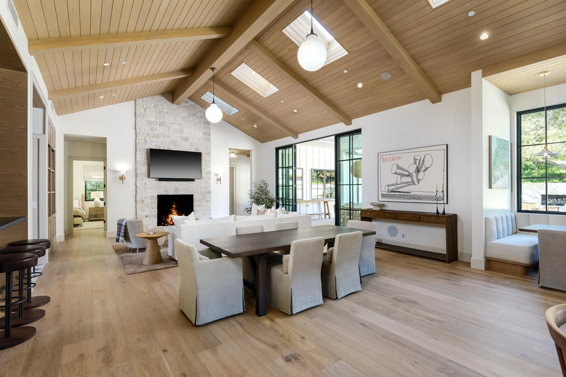 Dining and living spaces with a stone fireplace and timber ceiling